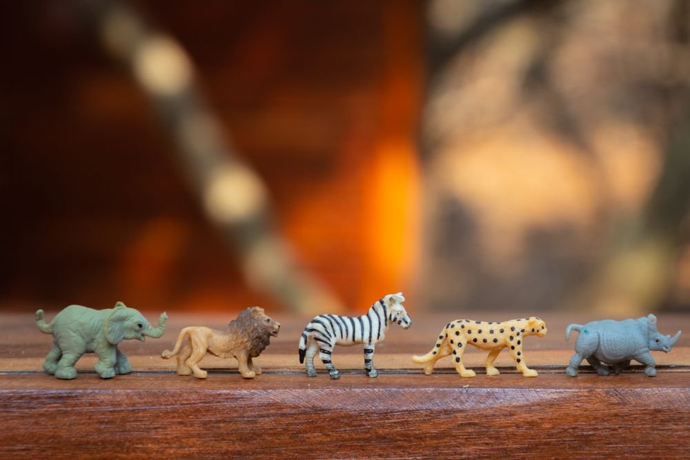 A row of miniature safari animal figures on a wooden surface