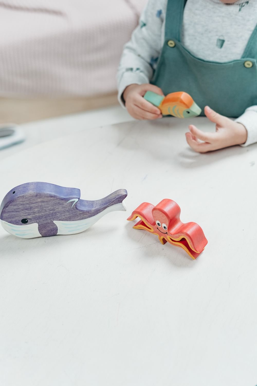 Small hands playing with colorful wooden sea-animal toys